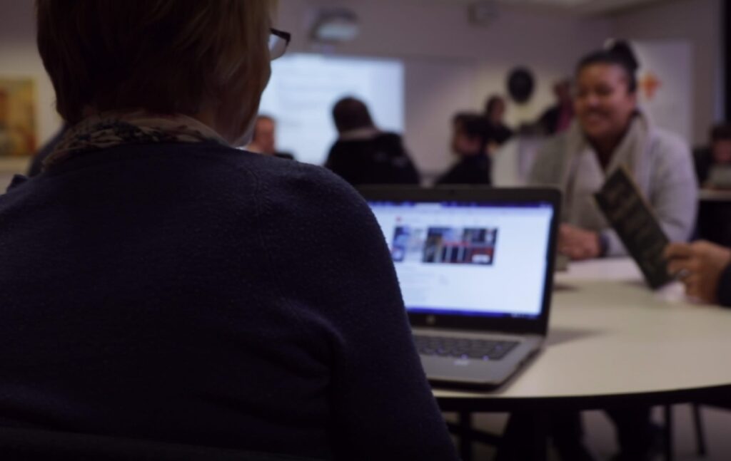 A woman in class looks at her open laptop